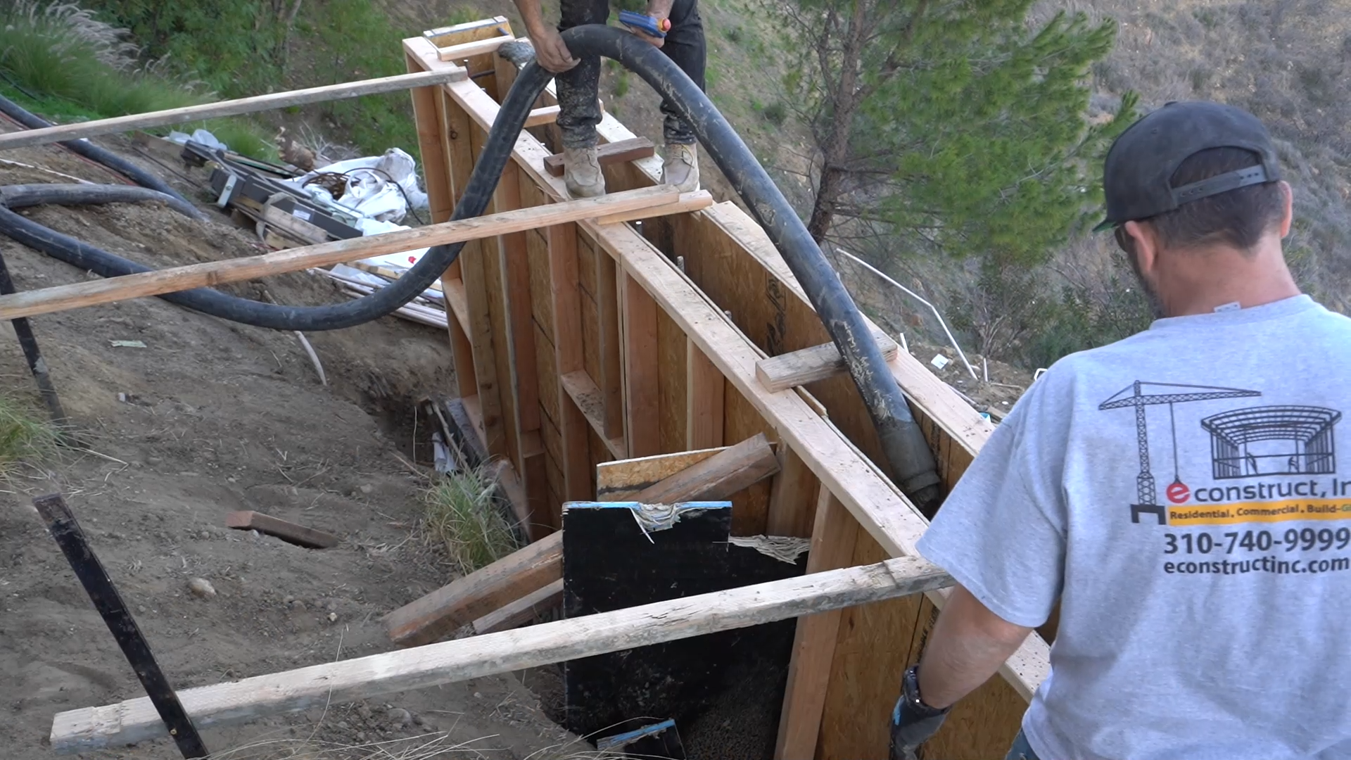 econstruct worker overseeing concrete pour into hillside forms at Bell Canyon