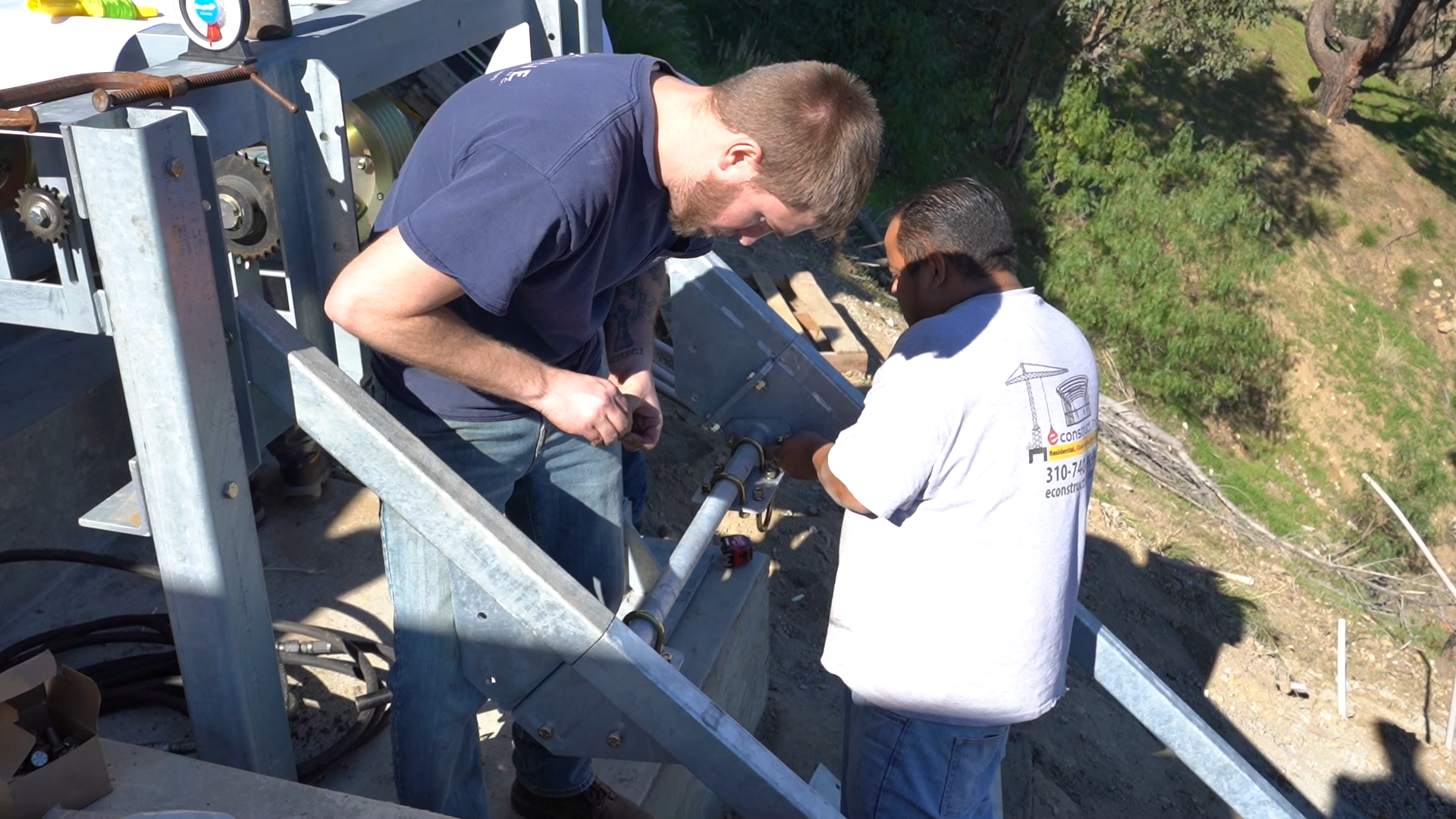 Two workers installing the lift drive mechanism and motor assembly at 50 Saddlebow
